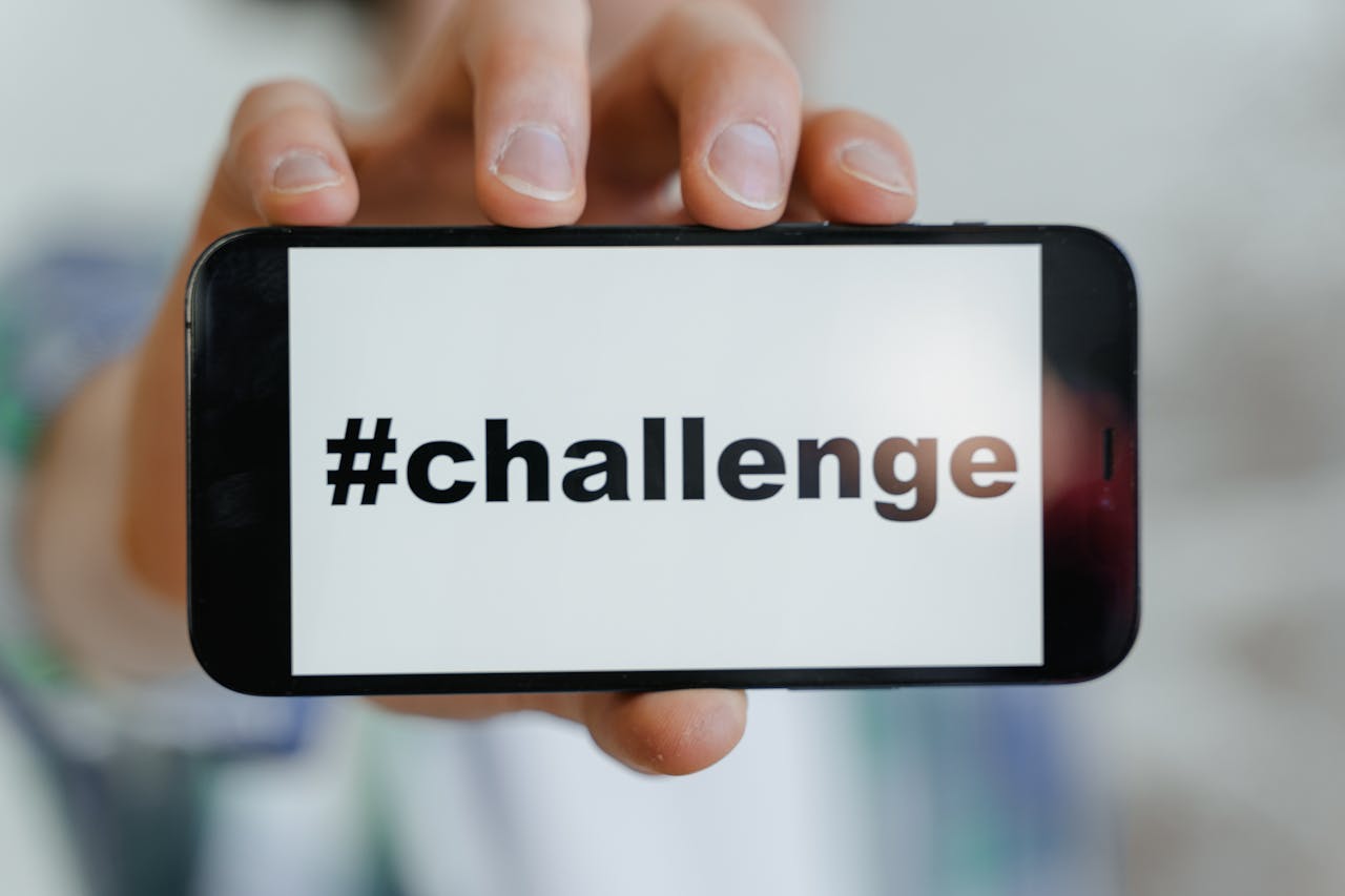 Close-up of a hand holding a smartphone displaying a #challenge hashtag.